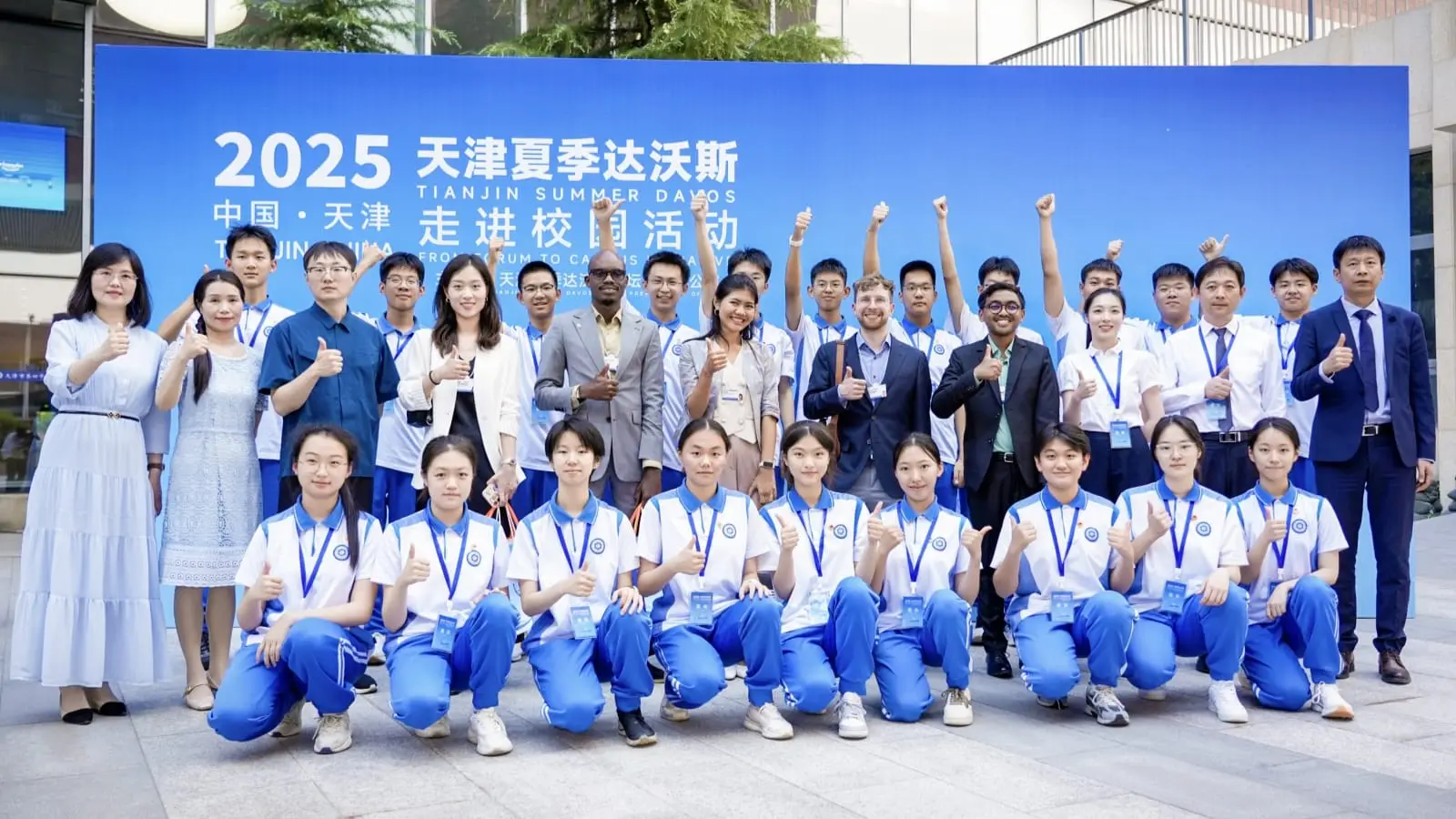 Group photograph at Tianjin No. 4 Middle School: students in school uniform kneeling in the front row, international guests and teachers standing behind them.