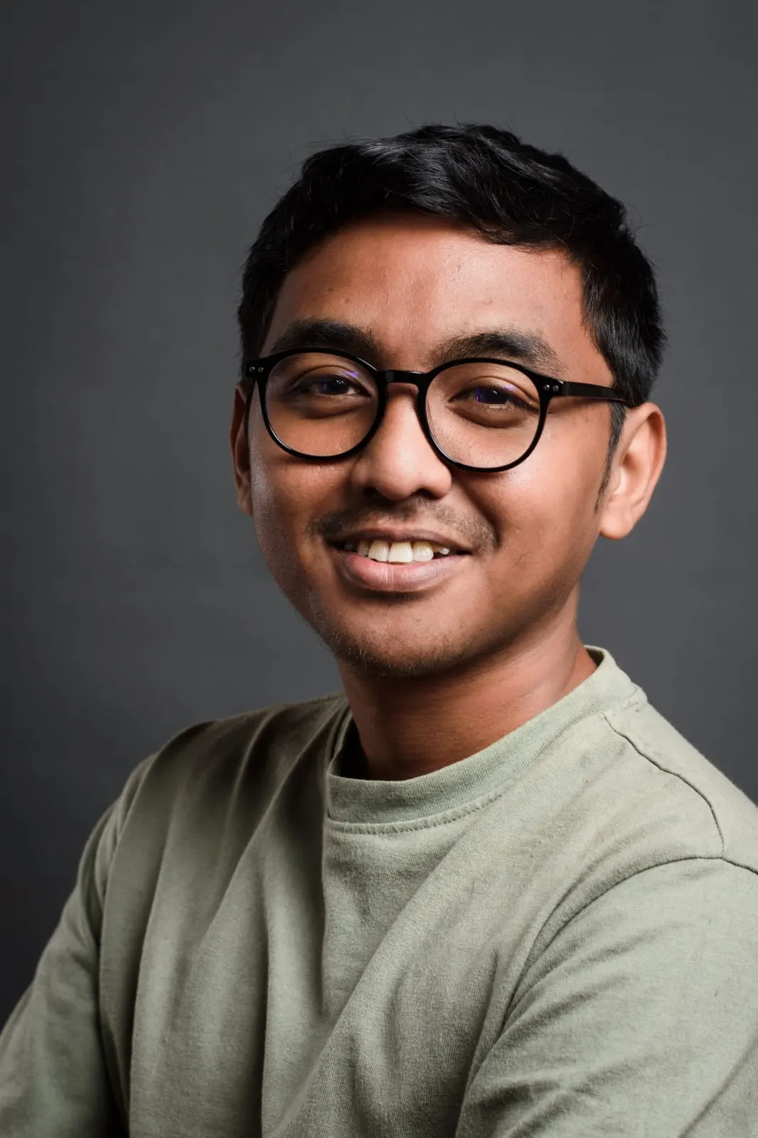 Mirado Rafenomahenintsoa, wearing glasses and a pale green T-shirt, against a plain grey background.